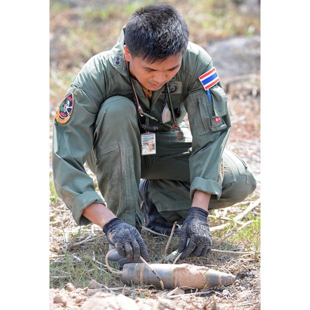 Тайский солдат, член команды по обезвреживанию боеприпасов, держит не взорвавшийся снаряд после перестрелки между войсками Таиланда и Камбоджи в провинции Сурин.