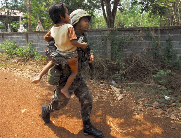Тайский солдат спасает деревенского мальчика во время перестрелки с камбоджийскими войсками неподалеку от храма Та Муэан на границе района Фаном Донг Рак провинции Сурин.