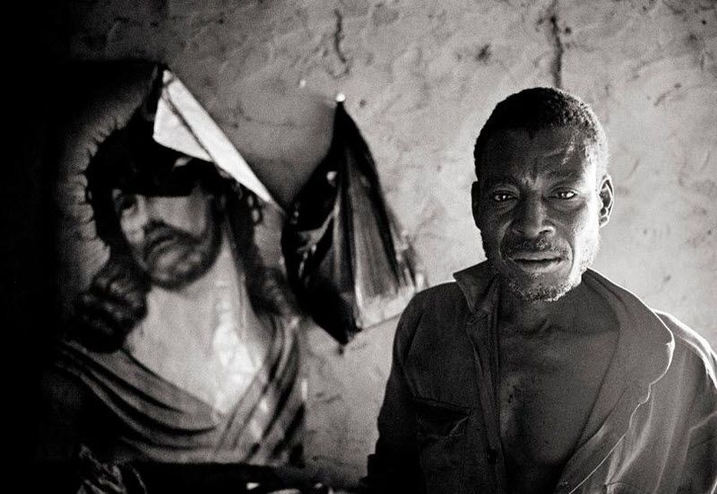 1 января 2011 года. -Купела, Буркина-Фасо – Сорокавосьмилетний Донатьен рядом с изображением Иисуса. Донатьен обнаружил, что он является ВИЧ-инфицированным, в 2006 году, анализы его жены были негативными. По данным исследования, проведенного ВОЗ в 2003 году, почти 15 процентов взрослых мужчин Буркина-Фасо имели более одного сексуального партнера в течение 12 месяцев – число резко контрастирует с тем, что менее чем 1 процент взрослых женщин в стране имели несколько партнеров.
