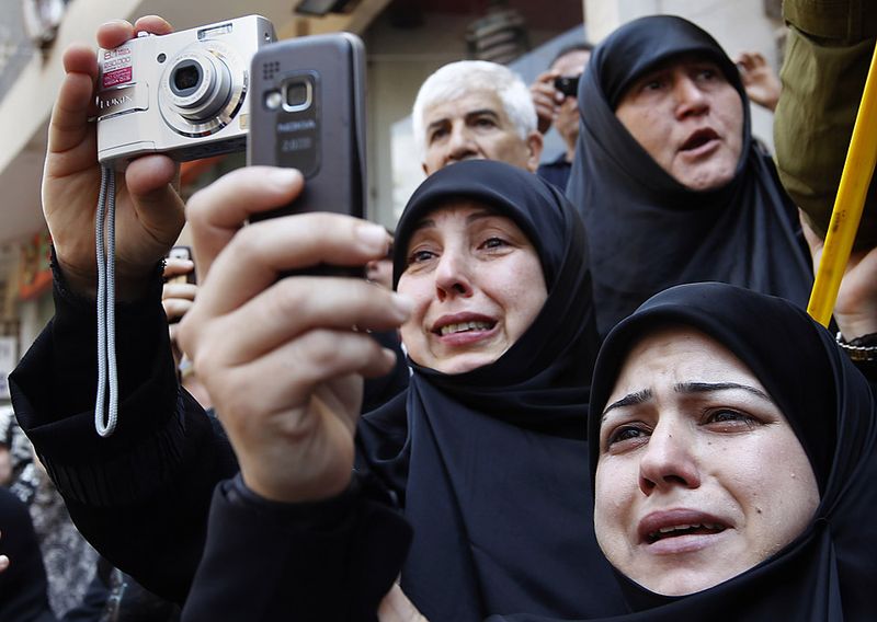 Шиитские женщины плачут, фотографируя гроб Сайида Мухаммада Хуссейна Фадлаллы в Бейруте. Десятки тысяч людей пришли проводить духовного лидера в последний путь. Он скончался в возрасте 75 лет после продолжительной болезни. (Hussein Malla/Associated Press)