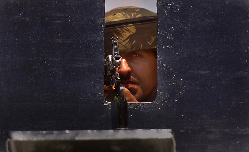 Индийский солдат испытывает свое оружие с крыши бронетранспортера во время патрулирования местности на окраине индийского города Шринагара. (Farooq Khan/European Pressphoto Agency)
