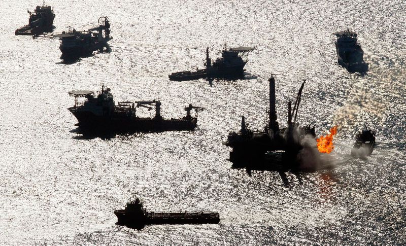Судна, помогающие убирать нефть после взрыва на «Deepwater Horizon», работают у берегов Мексиканского залива. Подводные роботы, управляемые инженерами, находящимися на милю выше, убрали задвижку над устьем скважины, чтобы заменить ее на более тугую, которая могла бы переливать нефть танкерам на поверхности. (AP Photo/Patrick Semansky)