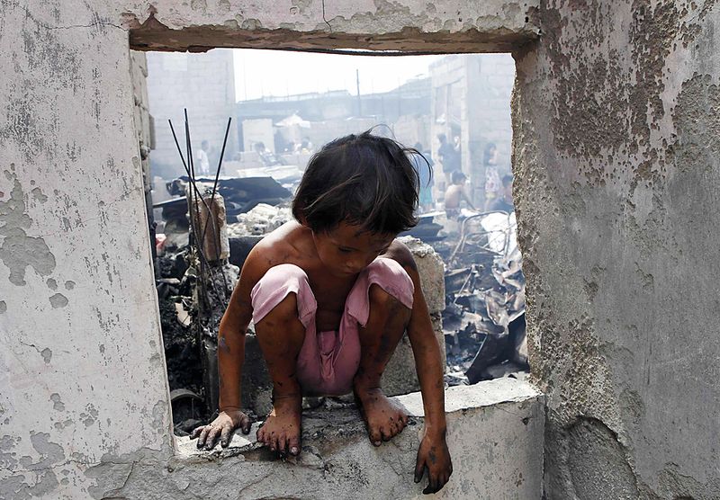 Мальчик ищет уцелевшие вещи на месте сгоревшего дома в пригороде Манилы Навотас. Во время пожара в филиппинской столице сгорело около 200 домов. Обошлось без жертв. (Romero Ranoco/Reuters)