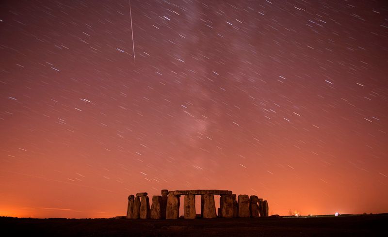 Метеор проносится мимо звезд в ночном небе над Стоунхенджем в Англии 12 августа. Персеиды возникают каждый августа, когда Земля проходит через поток космических обломков, оставленных кометой Свифта-Туттля. Фото сделано с помощью длинной экспозиции. (REUTERS/Kieran Doherty)