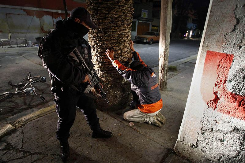 Федеральные полицейские обыскивают человека, подозреваемого в перевозке оружия и наркотиков во время антинаркотической операции в мексиканском Екатепек.